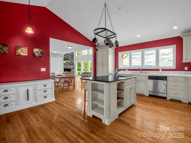 a kitchen with stainless steel appliances a stove a sink dishwasher and white cabinets with wooden floor