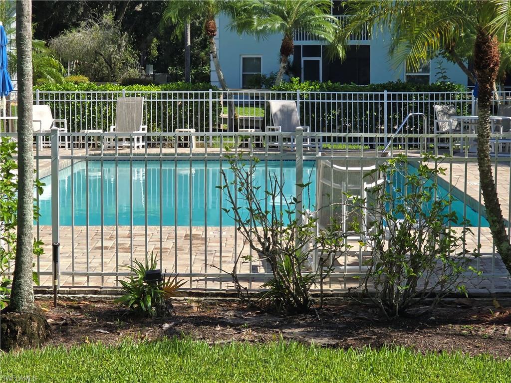 5737 Whitaker Road, Unit C104 Naples, FL 34112 - Photo 2 of 35 Community in-ground pool with surrounding paver decking and palm trees