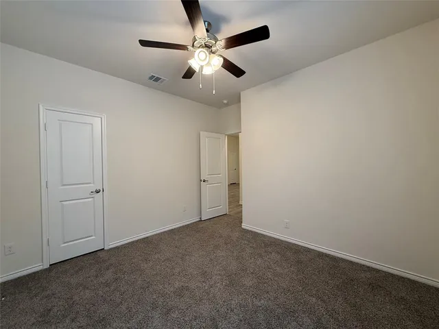 an empty room with a ceiling fan and a window