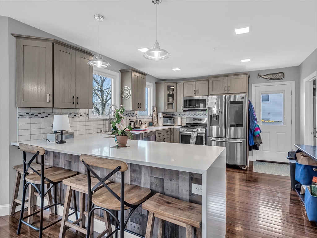 a kitchen with stainless steel appliances granite countertop a table chairs refrigerator and sink