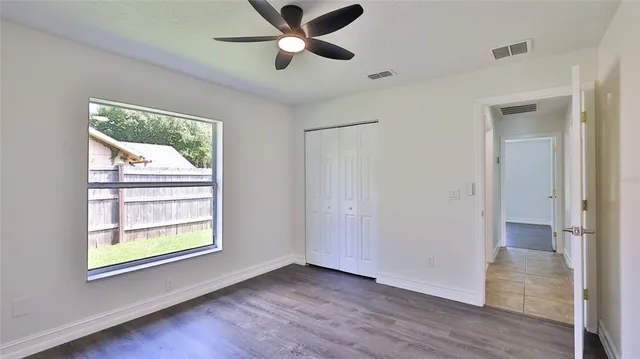 a view of an empty room with a window and wooden floor