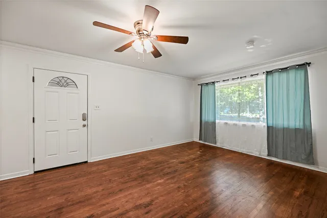 a view of an empty room with wooden floor and a window