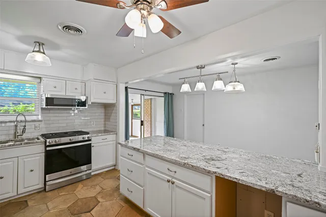 a kitchen with stainless steel appliances granite countertop a sink cabinets a stove and a refrigerator