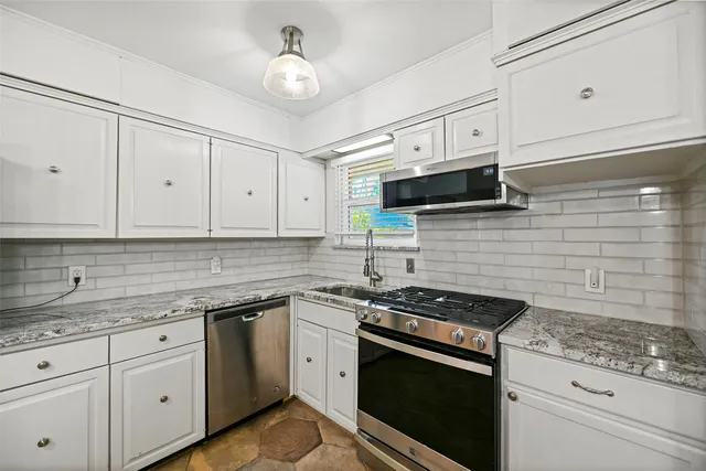 a kitchen with granite countertop white cabinets stainless steel appliances and a sink