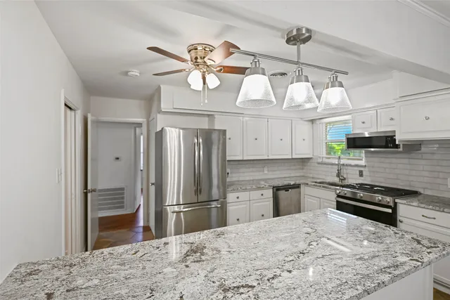 a kitchen with stainless steel appliances granite countertop a refrigerator a stove and a sink