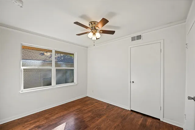 a view of an empty room with window and wooden floor