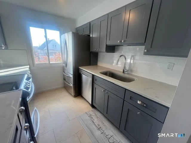 a kitchen with stainless steel appliances granite countertop a sink refrigerator and window