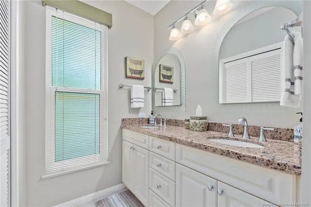 a bathroom with a granite countertop double vanity sink and mirror