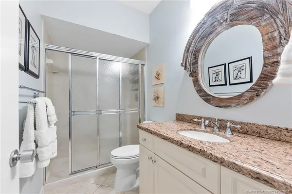 a bathroom with a granite countertop toilet sink and mirror