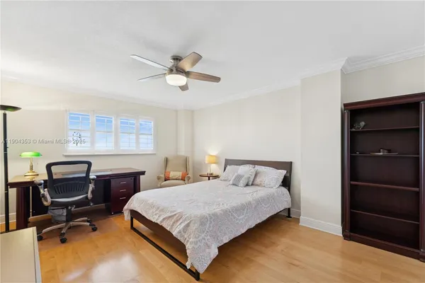 a bedroom with a bed a desk and chair with window