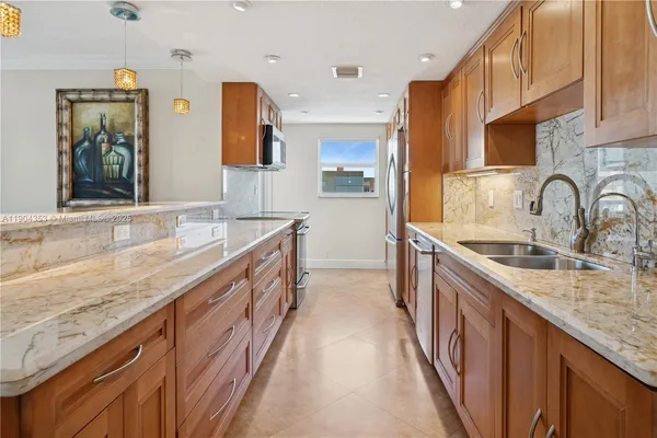 a large kitchen with stainless steel appliances granite countertop a sink and a refrigerator