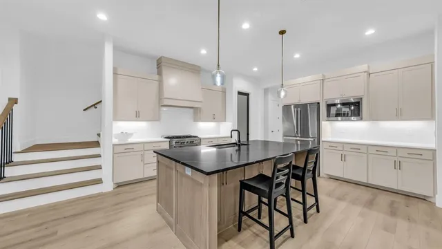 a large kitchen with stainless steel appliances granite countertop a lot of counter space and wooden floors