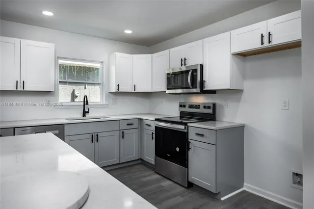 a kitchen with stainless steel appliances granite countertop a sink a stove top oven a counter space and cabinets