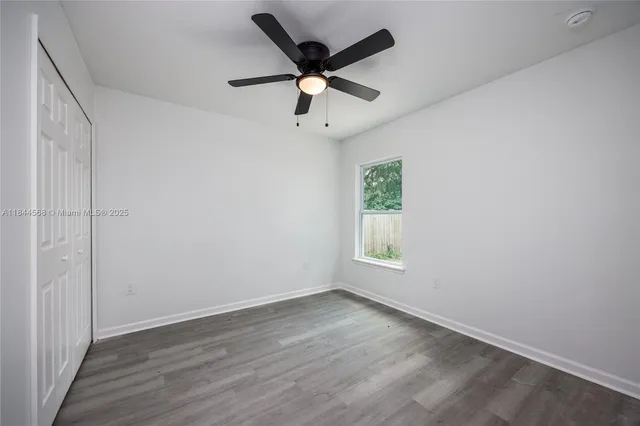 an empty room with wooden floor ceiling fan and windows