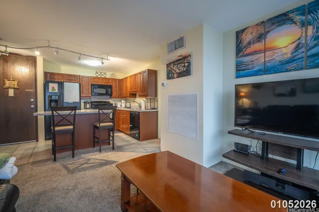 a living room with stainless steel appliances furniture and a flat screen tv