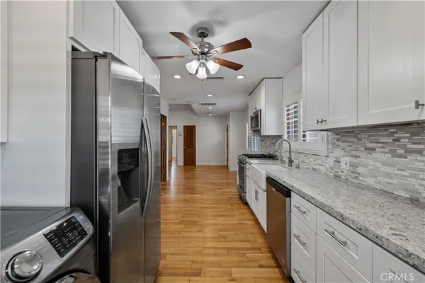 a kitchen with stainless steel appliances granite countertop a sink refrigerator and cabinets
