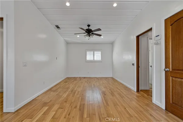 a view of empty room with wooden floor and fan