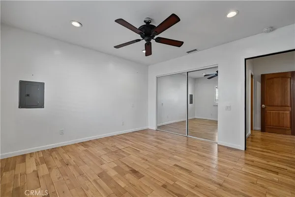 a view of empty room with wooden floor and ceiling fan