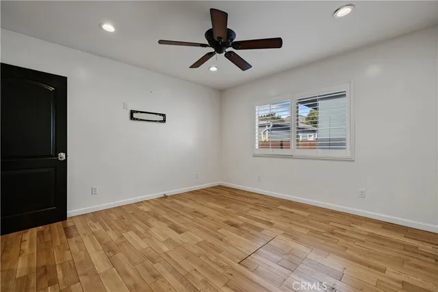 a view of empty room with wooden floor and ceiling fan