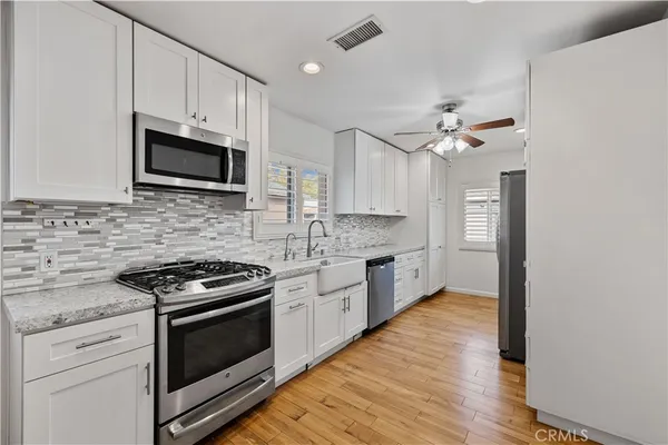 a kitchen with stainless steel appliances white cabinets a sink dishwasher a stove and a microwave oven with white cabinets