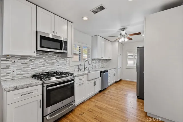 a kitchen with stainless steel appliances white cabinets a sink dishwasher a stove and a microwave oven with white cabinets