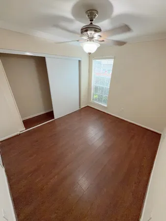 an empty room with windows and fan