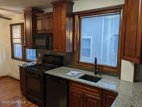 a kitchen with granite countertop a sink a stove and cabinets