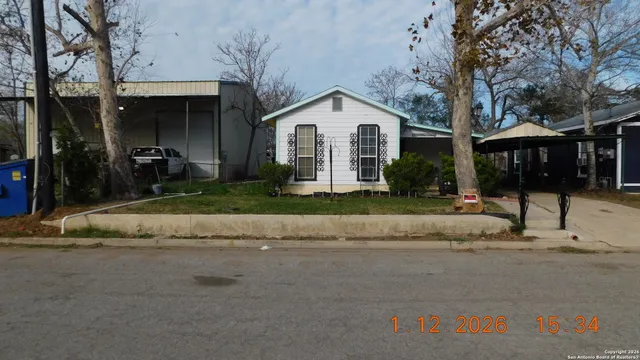 a view of a white house with a yard and large tree