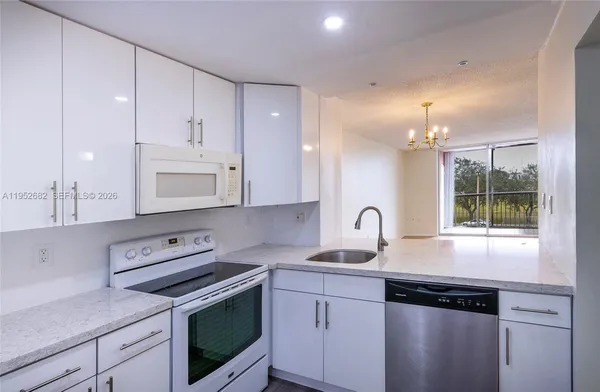 a kitchen with granite countertop a sink a stove a refrigerator and cabinets