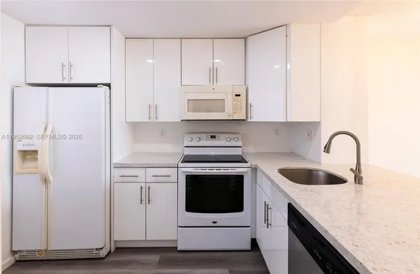 a kitchen with granite countertop white cabinets and white stainless steel appliances
