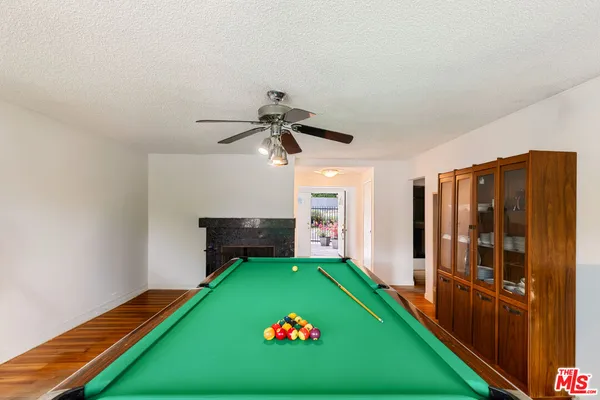 an empty room with wooden floor chandelier fan and windows