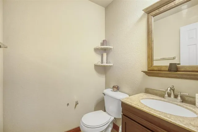 a bathroom with a granite countertop toilet sink and mirror