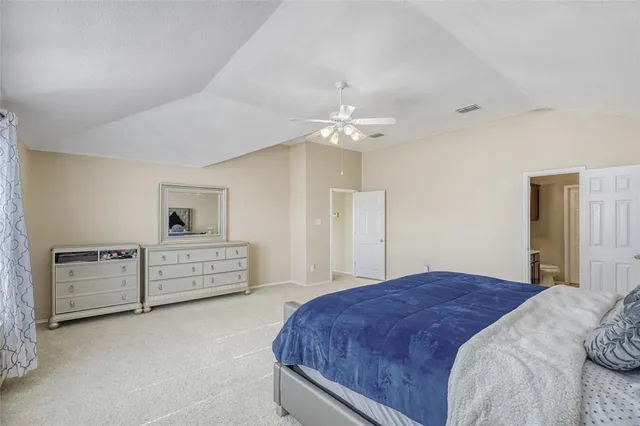 a spacious bedroom with a large bed and a chandelier