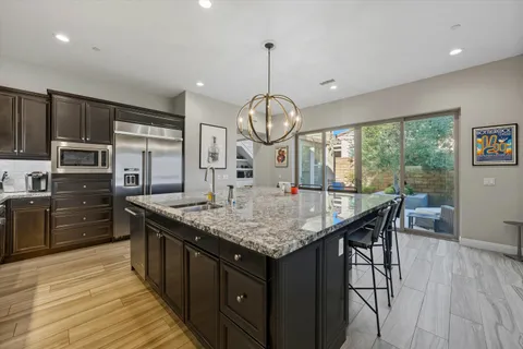 a kitchen with stainless steel appliances granite countertop a kitchen island hardwood floor sink stove dining table and chairs