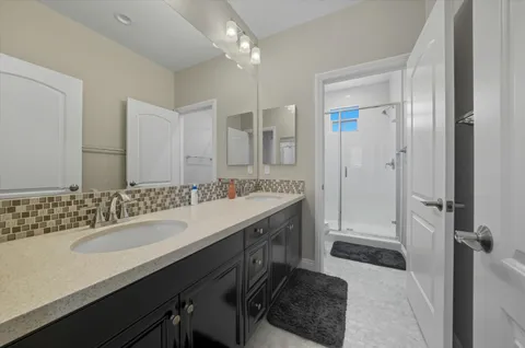 a bathroom with a sink double vanity granite tub shower and a mirror