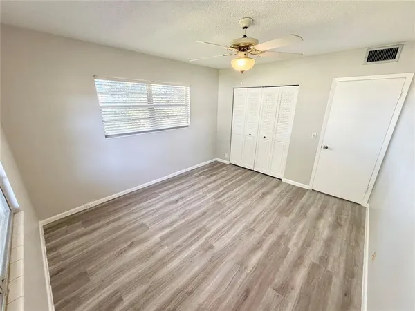 an empty room with windows and fan