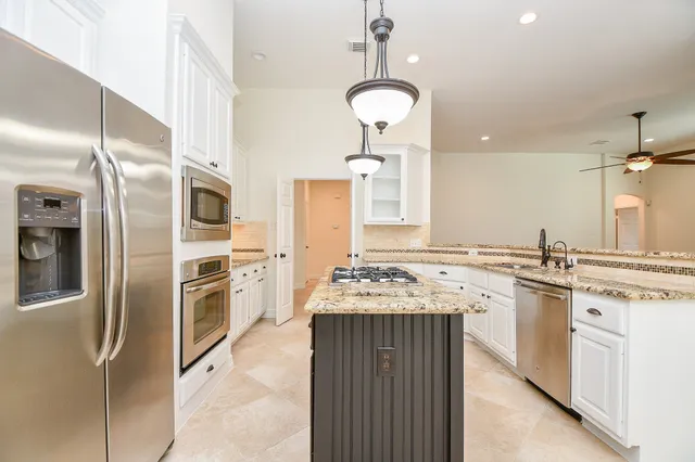 a kitchen with granite countertop a sink stove and refrigerator