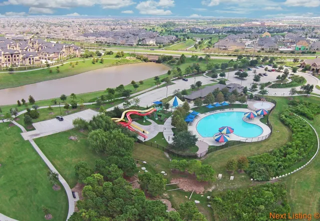 an aerial view of a residential houses with outdoor space and a lake view in back