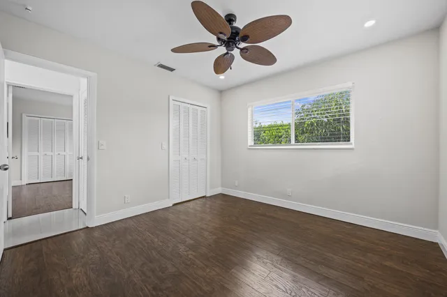 an empty room with wooden floor and a ceiling fan
