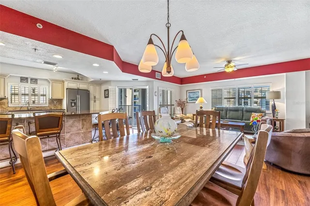 a view of a dining room with furniture one side kitchen view and wooden floor