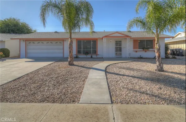 front view of house with a yard and palm trees
