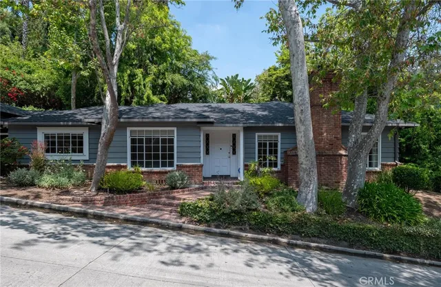a front view of a house with garden and trees