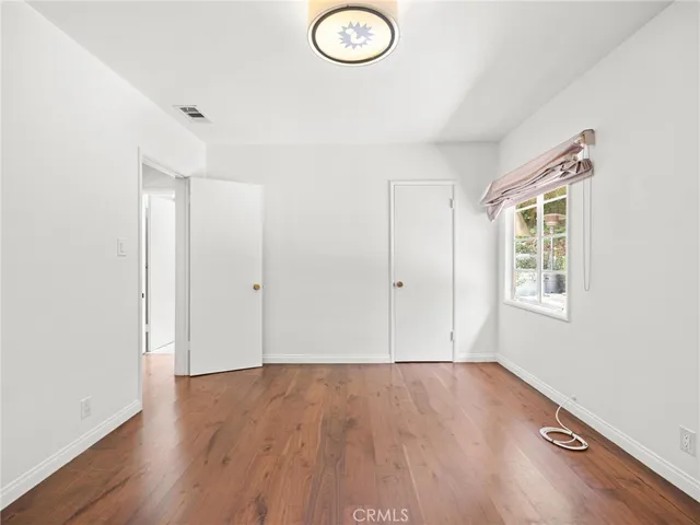 an empty room with wooden floor and window