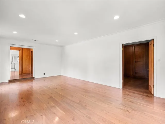 a view of an empty room with wooden floor and closet