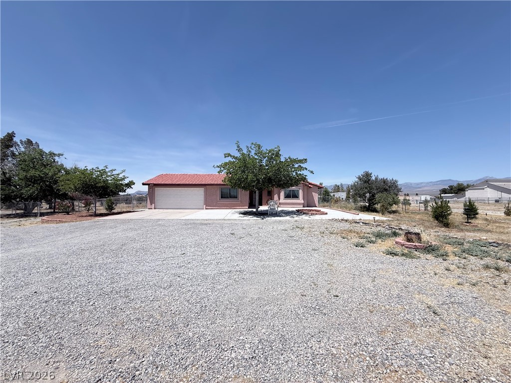 1220 East Gamebird Road Pahrump, NV 89048 - Photo 32 of 49 A terracotta-roofed ranch home stands amidst a spacious gravel lot, offering a wide-open rural setting.