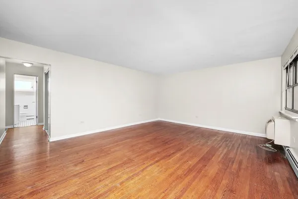 a view of empty room with wooden floor and fireplace