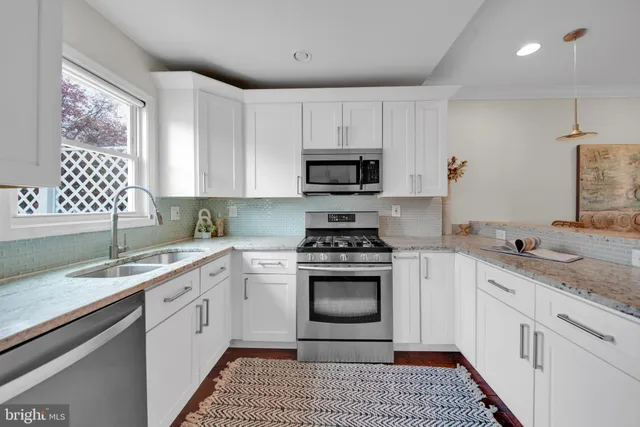 a kitchen with granite countertop a sink stove and cabinets