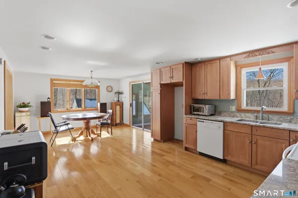 a open kitchen with stainless steel appliances granite countertop a stove top oven a sink dishwasher a dining table and chairs with wooden floor