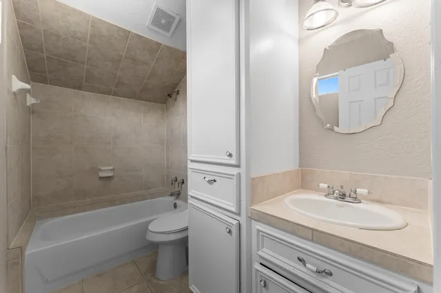 a bathroom with a granite countertop sink a toilet and a bathtub