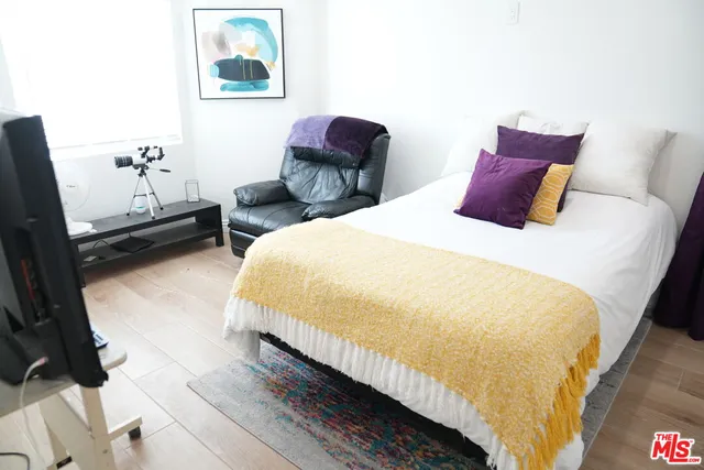 a bedroom with bed and a painting on the wall